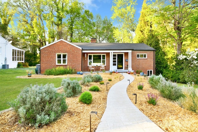 ranch-style home with brick siding, a porch, a chimney, and a front lawn