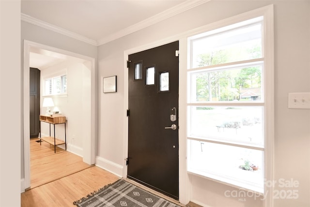 entryway with wood finished floors, baseboards, and ornamental molding