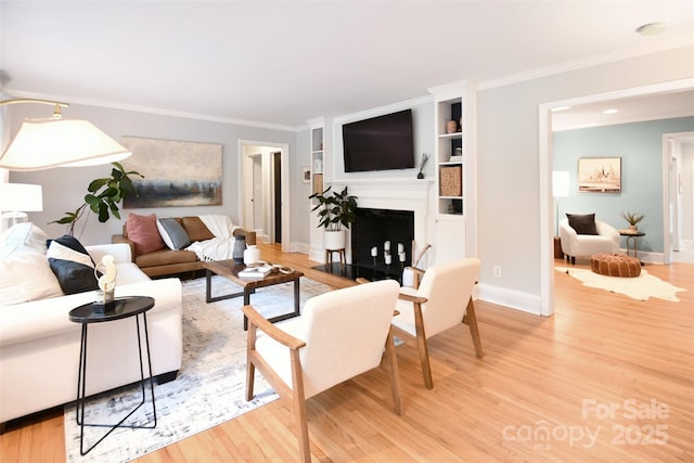living room with light wood-style floors, crown molding, a fireplace, and baseboards