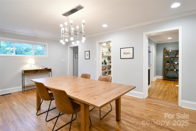 dining area featuring ornamental molding, visible vents, light wood finished floors, and a notable chandelier