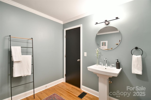 bathroom featuring visible vents, baseboards, crown molding, and wood finished floors