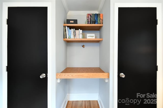 interior space featuring crown molding, baseboards, and wood finished floors
