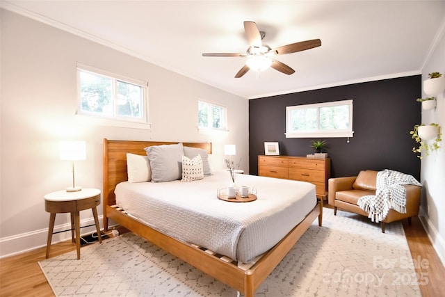 bedroom with crown molding, baseboards, light wood-type flooring, and a ceiling fan