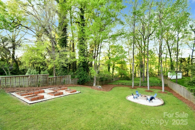 view of yard featuring a fire pit, a fenced backyard, and a vegetable garden