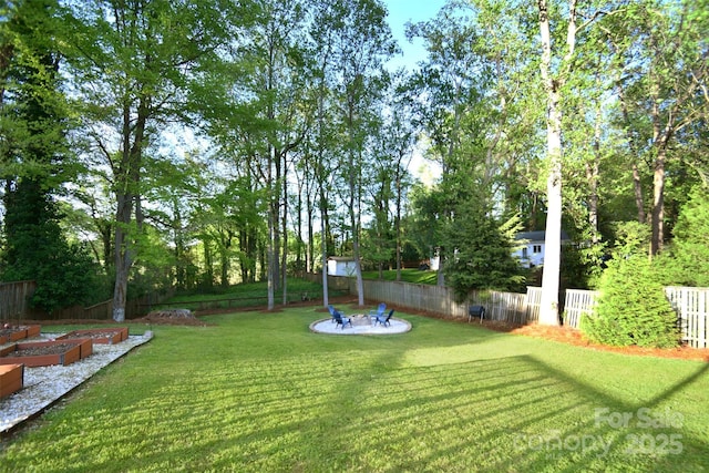 view of yard with an outdoor fire pit, a vegetable garden, and fence