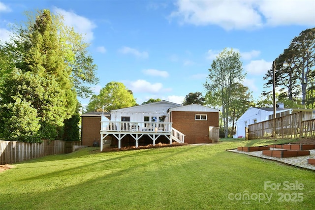 rear view of property featuring a yard, a wooden deck, and fence