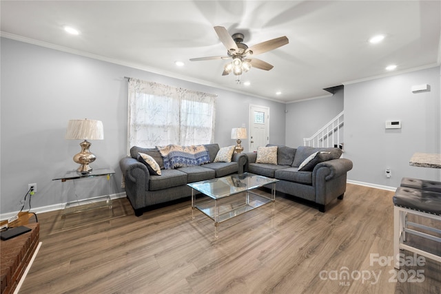 living area with ornamental molding, a ceiling fan, recessed lighting, wood finished floors, and stairs