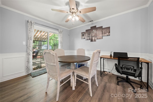 dining area with ornamental molding, visible vents, wainscoting, and wood finished floors