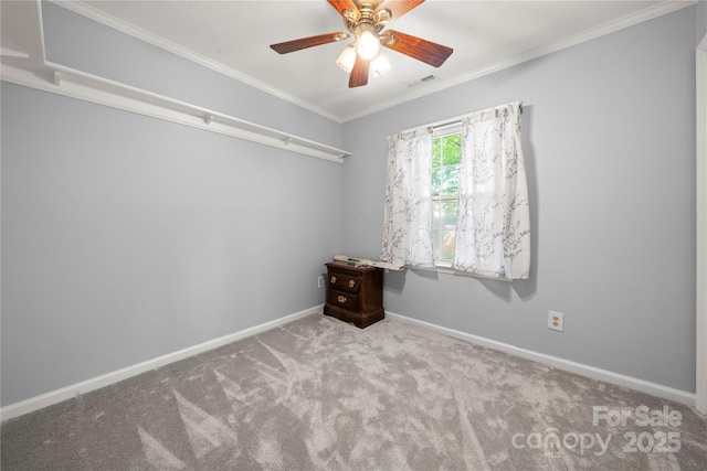 carpeted spare room featuring ceiling fan, baseboards, ornamental molding, and visible vents
