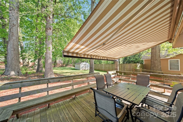 wooden deck with outdoor dining area, an outdoor structure, a fenced backyard, and a storage shed