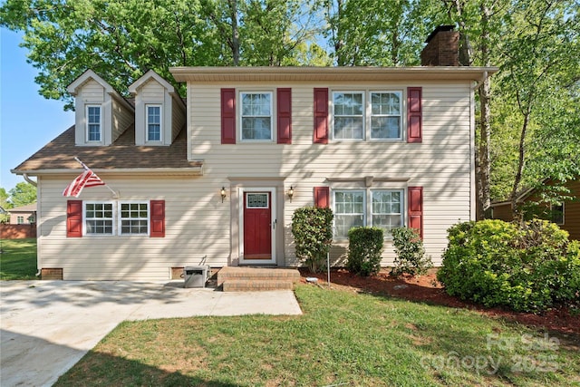 colonial home featuring a chimney and a front yard