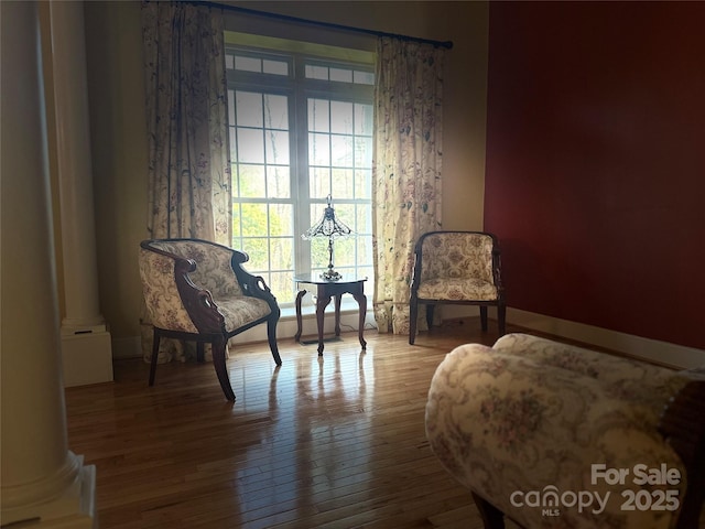 sitting room featuring baseboards, ornate columns, and hardwood / wood-style floors