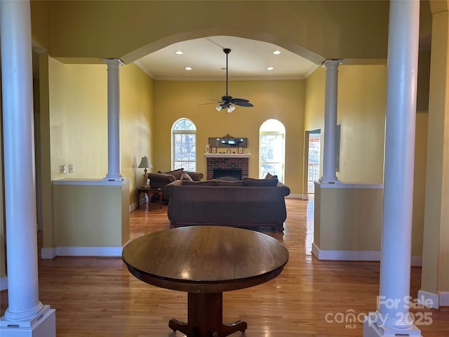 living room featuring a brick fireplace, baseboards, a ceiling fan, and wood finished floors