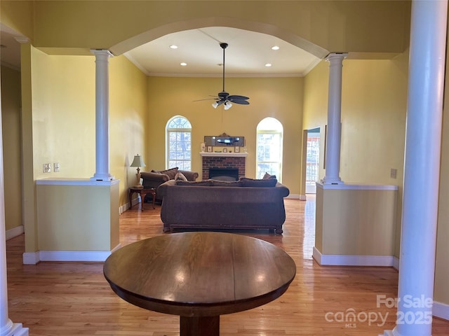 living room featuring crown molding, ceiling fan, decorative columns, and light wood finished floors