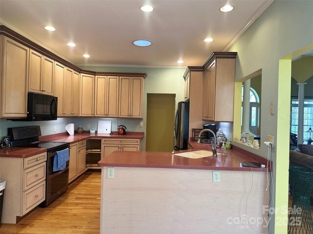 kitchen with crown molding, a peninsula, black appliances, a sink, and light wood finished floors