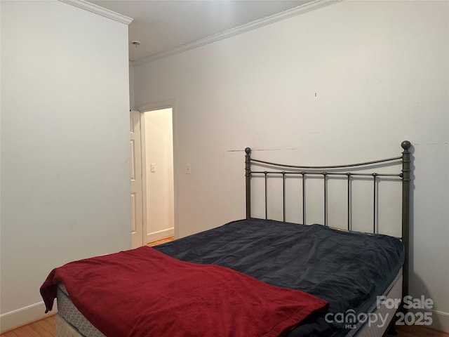 bedroom featuring baseboards, crown molding, and wood finished floors