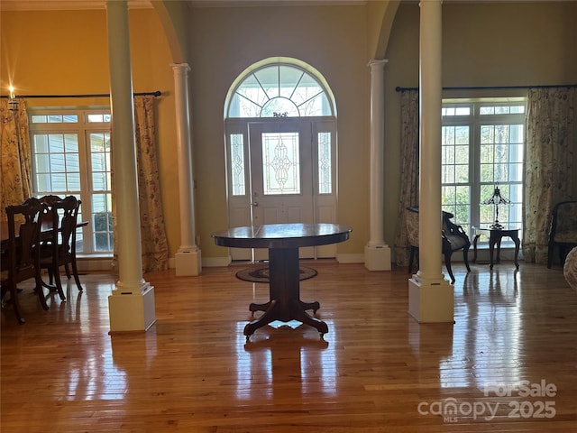 foyer entrance with wood finished floors, decorative columns, a towering ceiling, and baseboards