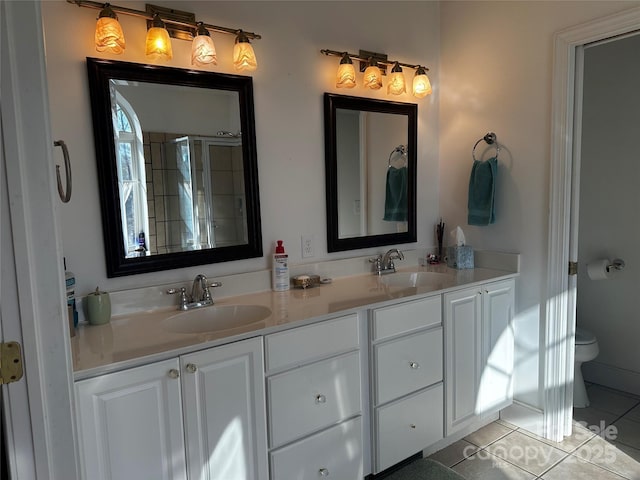 bathroom with tile patterned floors, double vanity, a sink, and toilet