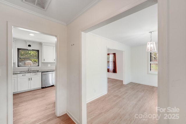 hallway with crown molding, visible vents, baseboards, and light wood-type flooring