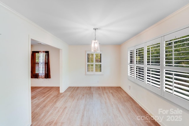 spare room with a chandelier, baseboards, ornamental molding, and wood finished floors