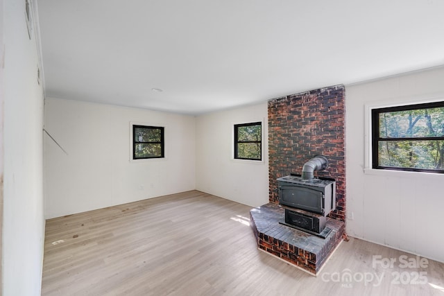 living room with a healthy amount of sunlight, a wood stove, and wood finished floors