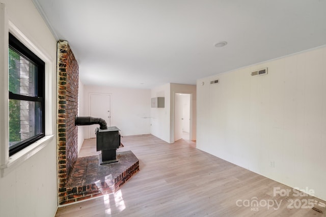 living room featuring a wood stove, visible vents, and light wood-type flooring