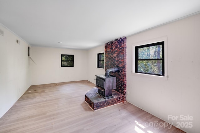 living area featuring a wood stove, visible vents, crown molding, and wood finished floors
