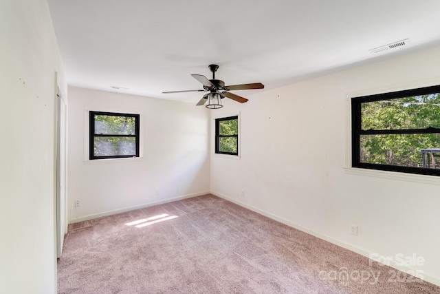 carpeted spare room featuring visible vents, baseboards, and ceiling fan