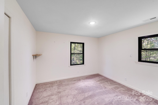carpeted empty room featuring baseboards and visible vents