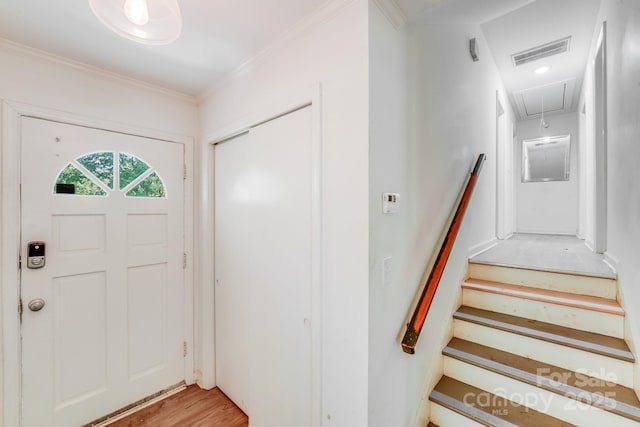 foyer entrance featuring ornamental molding, visible vents, stairway, and light wood-style floors
