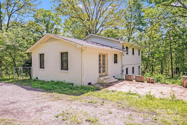 rear view of property featuring brick siding, entry steps, fence, and a shingled roof
