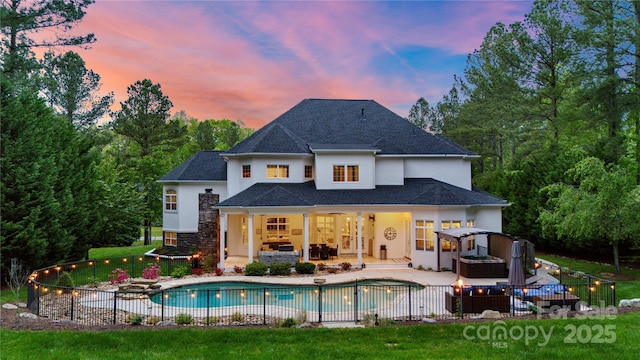 133 Crooked Branch Way, Troutman, NC 28166 - back of house at dusk featuring a fenced in pool, stucco siding, a jacuzzi, and a patio area