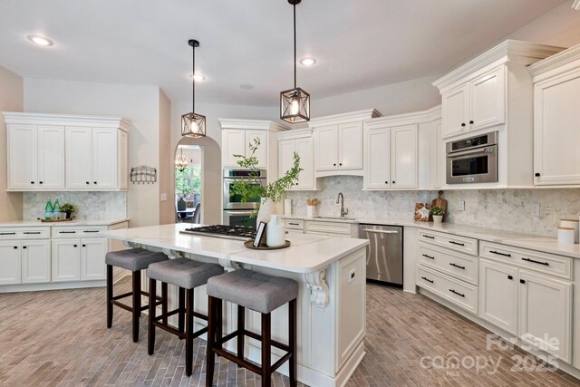 133 Crooked Branch Way, Troutman, NC 28166 - kitchen featuring appliances with stainless steel finishes, light countertops, backsplash, white cabinetry, and a center island