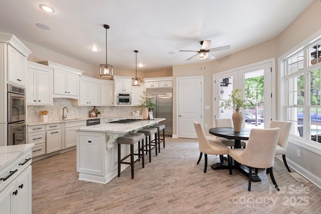 133 Crooked Branch Way, Troutman, NC 28166 - kitchen featuring a kitchen breakfast bar, appliances with stainless steel finishes, a center island, a ceiling fan, and backsplash