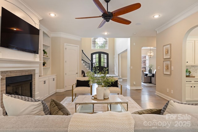 133 Crooked Branch Way, Troutman, NC 28166 - living room with arched walkways, wood finished floors, ceiling fan with notable chandelier, a brick fireplace, and baseboards