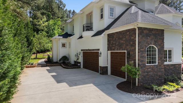 133 Crooked Branch Way, Troutman, NC 28166 - view of side of home featuring stucco siding, driveway, stone siding, a balcony, and an attached garage