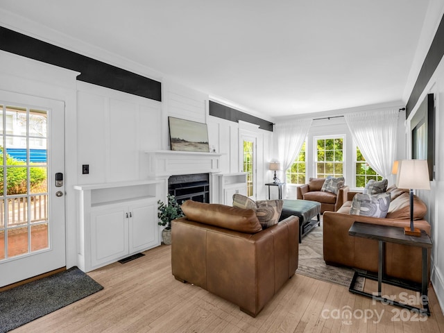 201 W 6th St, Rutherfordton, NC 28139 - living area featuring light wood-style flooring, a fireplace, crown molding, and a decorative wall