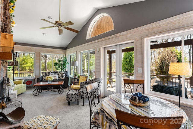 sunroom / solarium with carpet floors, wooden walls, high vaulted ceiling, and french doors