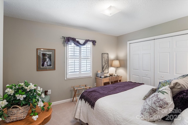 bedroom with carpet flooring, a textured ceiling, baseboards, and a closet