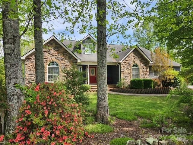 view of front facade with stone siding and a front lawn