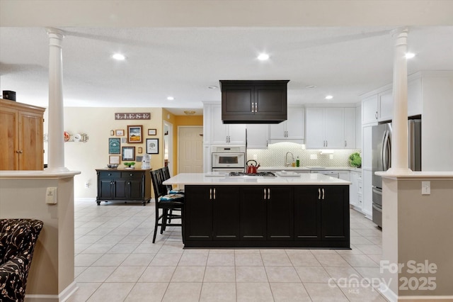 kitchen with decorative columns, light countertops, light tile patterned floors, freestanding refrigerator, and oven