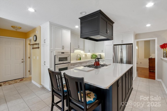 kitchen featuring light tile patterned flooring, light countertops, white cabinets, appliances with stainless steel finishes, and backsplash