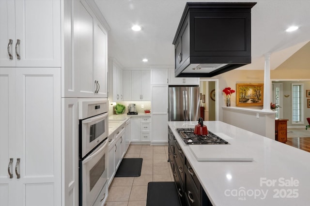 kitchen with light countertops, appliances with stainless steel finishes, light tile patterned floors, and white cabinets