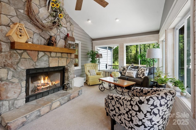 living room featuring carpet flooring, a ceiling fan, a stone fireplace, and lofted ceiling
