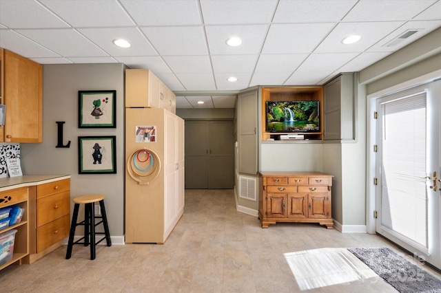 interior space with baseboards, a drop ceiling, and visible vents