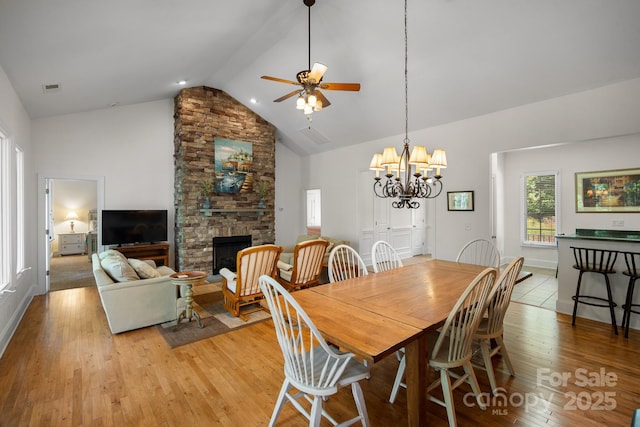 591 Emerald Isle Ct, Lexington, NC 27292 - dining area featuring ceiling fan with notable chandelier, high vaulted ceiling, a fireplace, light wood-style flooring, and visible vents