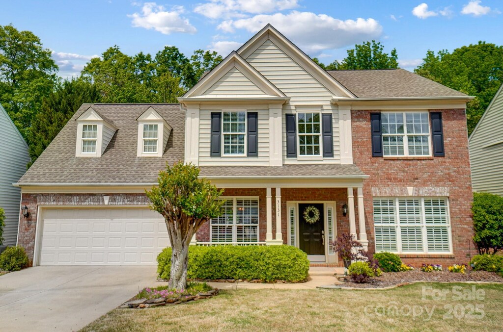 3131 Arborhill Rd, Charlotte, NC 28270 - traditional-style house featuring a front lawn, driveway, a shingled roof, a porch, and brick siding