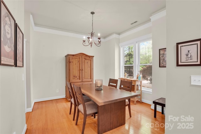 dining room featuring light wood-style floors, a notable chandelier, visible vents, and baseboards