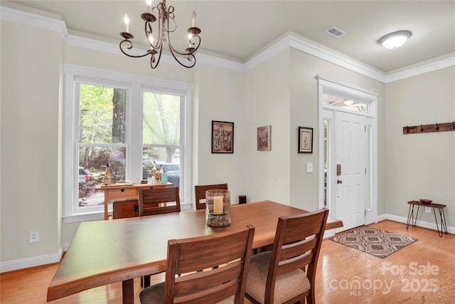 dining space featuring crown molding, baseboards, light wood-type flooring, and an inviting chandelier