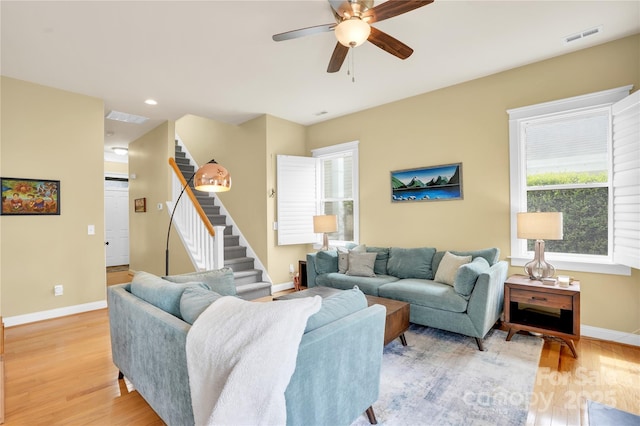 living area with stairs, light wood-style flooring, baseboards, and visible vents